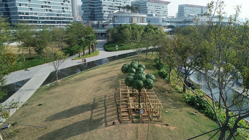 Urban Forest, Oh Bay Sculpture Park, Shenzhen, China, 2021. Metal and augmented reality. Metal sculptures of trees are situated in the middle of a grassy lawn surrounded by real trees.