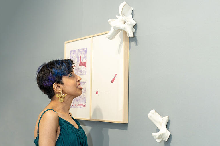 Pinka looking up at and wearing her work, "Time Out Of (Skeletal) Joint: The Spineless Don’t Protest—Considerations"